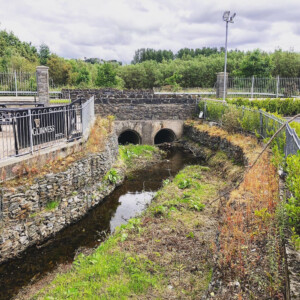 Twin culvert outfall discharging into a stone lined channel behind railings