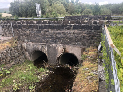 Stone bridge with twin culvert pipes carrying a watercourse beneath it