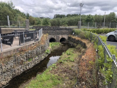 Culvert outfall and stone lined channel viewed from the roadside railings