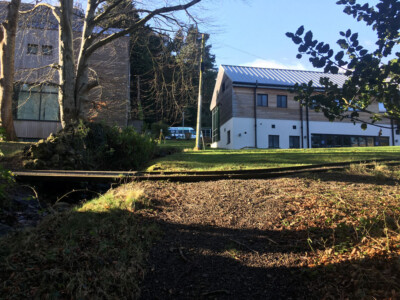 Watercourse running in front of modern school buildings in low winter sun