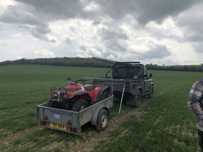 Four wheel drive and quad bike on a trailer at the edge of a green field