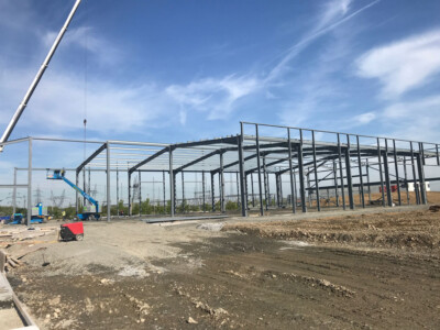 Steel portal frame building under construction with a cherry picker