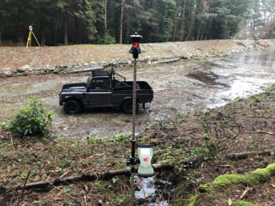 Survey prism on a tripod beside a pickup on a cleared forest track