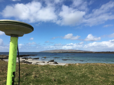 GNSS antenna on a survey pole with a beach and island in the background