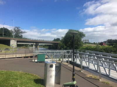 Riverside walkway and road bridge with a GNSS pole in the foreground