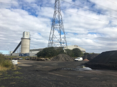 Industrial yard with a lattice tower, silo and stockpiled material