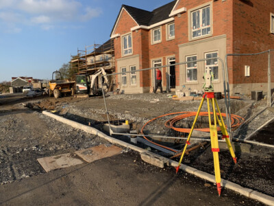 Total station set up at a new build house beside an open services trench
