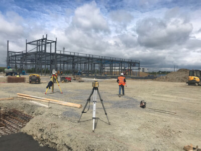 Surveyors with a tripod at a steel framed building under construction