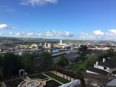 Elevated view over a city, its river and docks from a landscaped garden