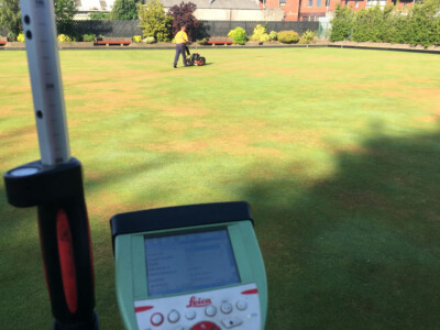 Survey controller in the foreground of a bowling green being mown